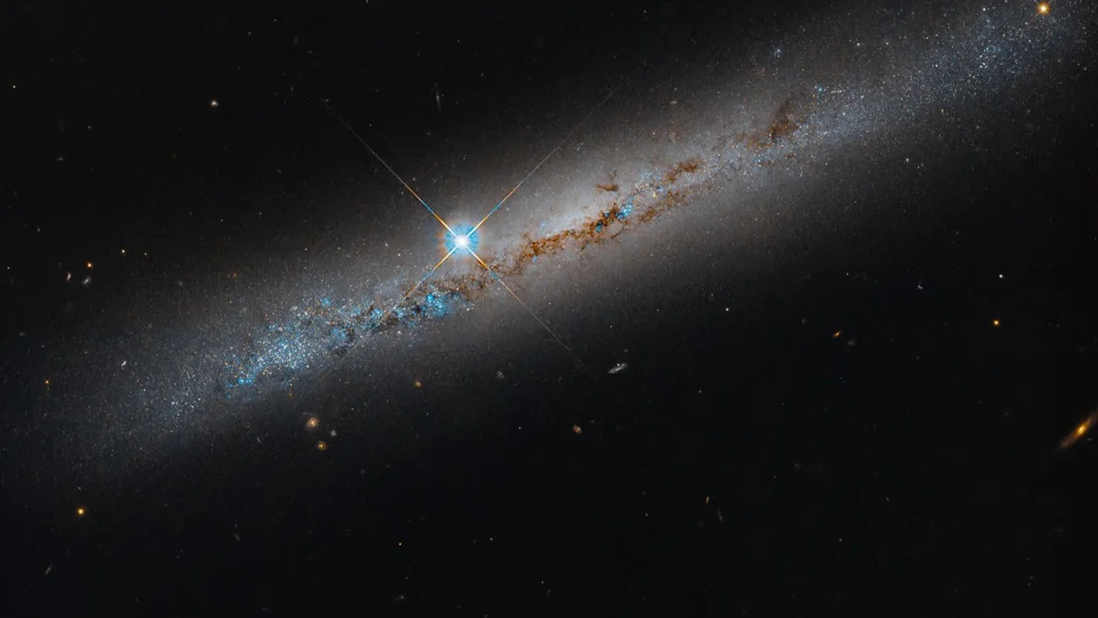La galaxie NGC 1827 vue par la tranche, avec des bandes de poussière et une étoile au premier plan.